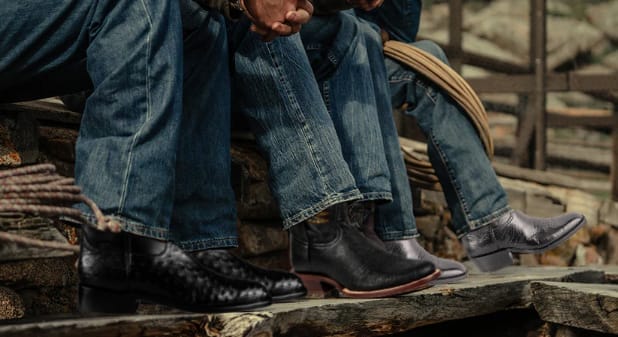Men's black cowboy boots while wearing jeans